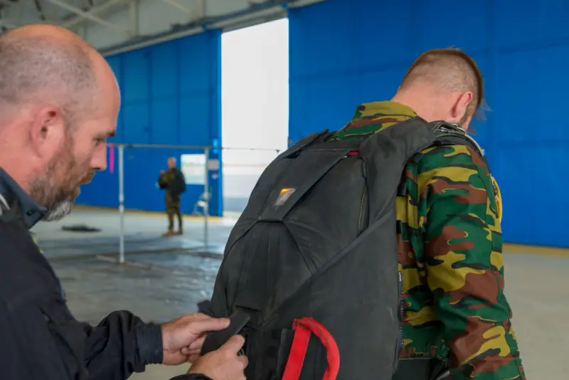 Controle van een parachute tijdens Belgische parachutistentraining in Chièvres