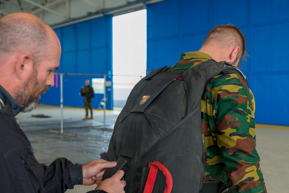 Controle van een parachute tijdens Belgische parachutistentraining in Chièvres